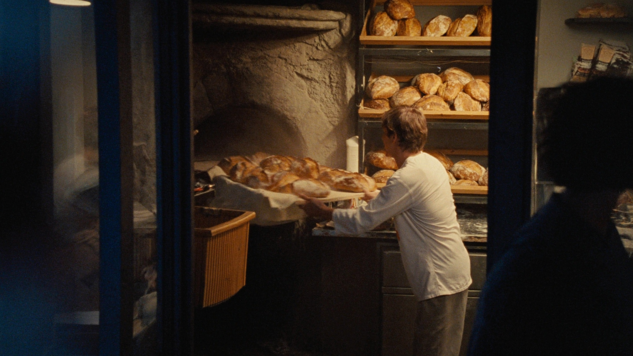 Bäcker zieht frische, goldene Brote aus dem Steinofen der Bäckerei Bühler