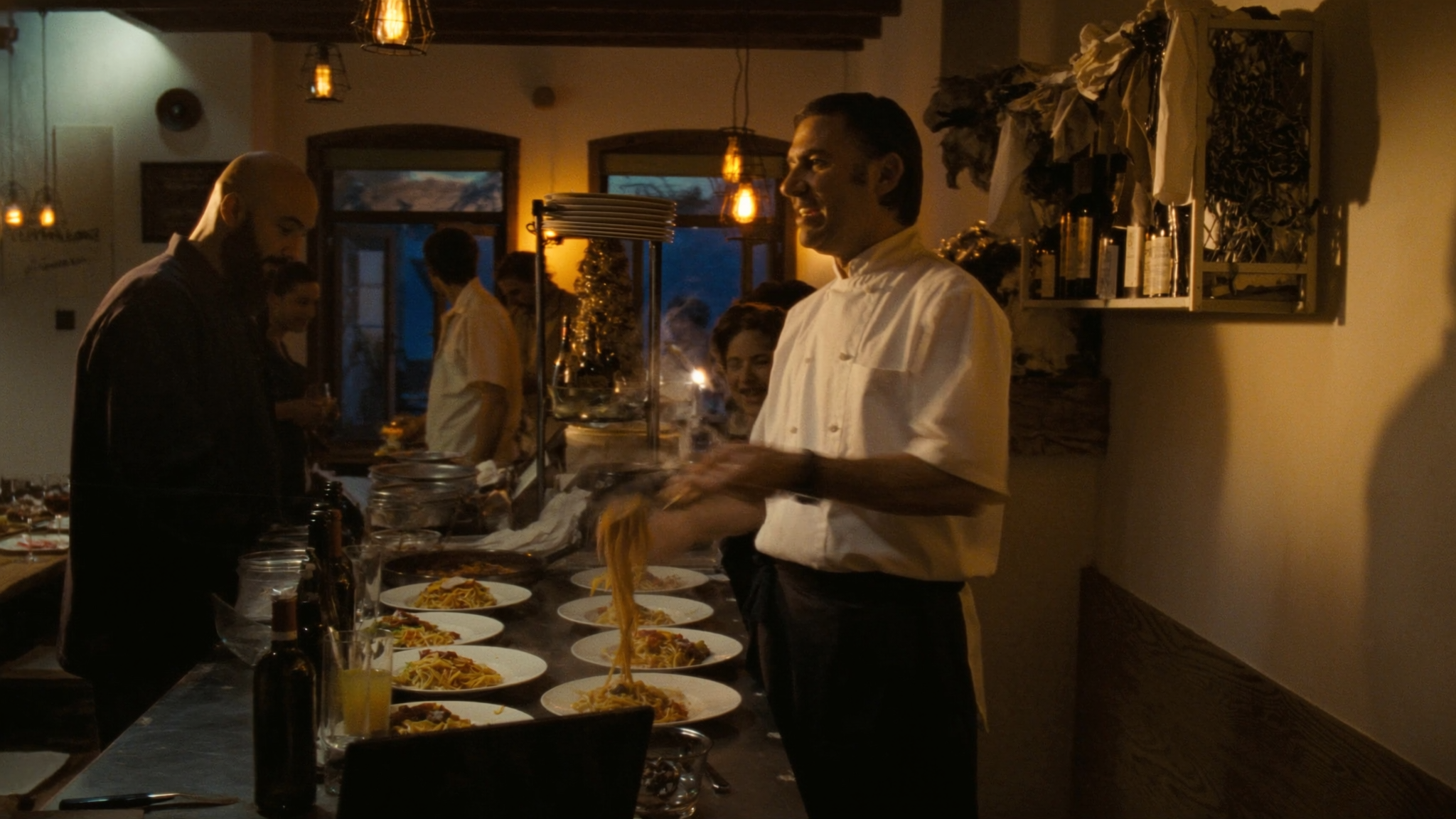 Koch richtet frische Pasta an in der warmen Trattoria Greco am Abend